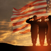 USA army soldiers saluting on a background of sunset or sunrise and USA flag. Greeting card for Veterans Day, Memorial Day, Independence Day. America celebration.