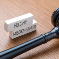 A judge’s gavel next to wooden blocks labeled Felony and Misdemeanor. Legal terms, criminal charges, and judicial concepts in law and justice concept.